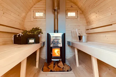 Innenansicht der Fasssauna mit Kamin und Aufguss